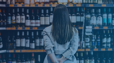 Mulher olha para uma prateleira de vinhos num supermercado